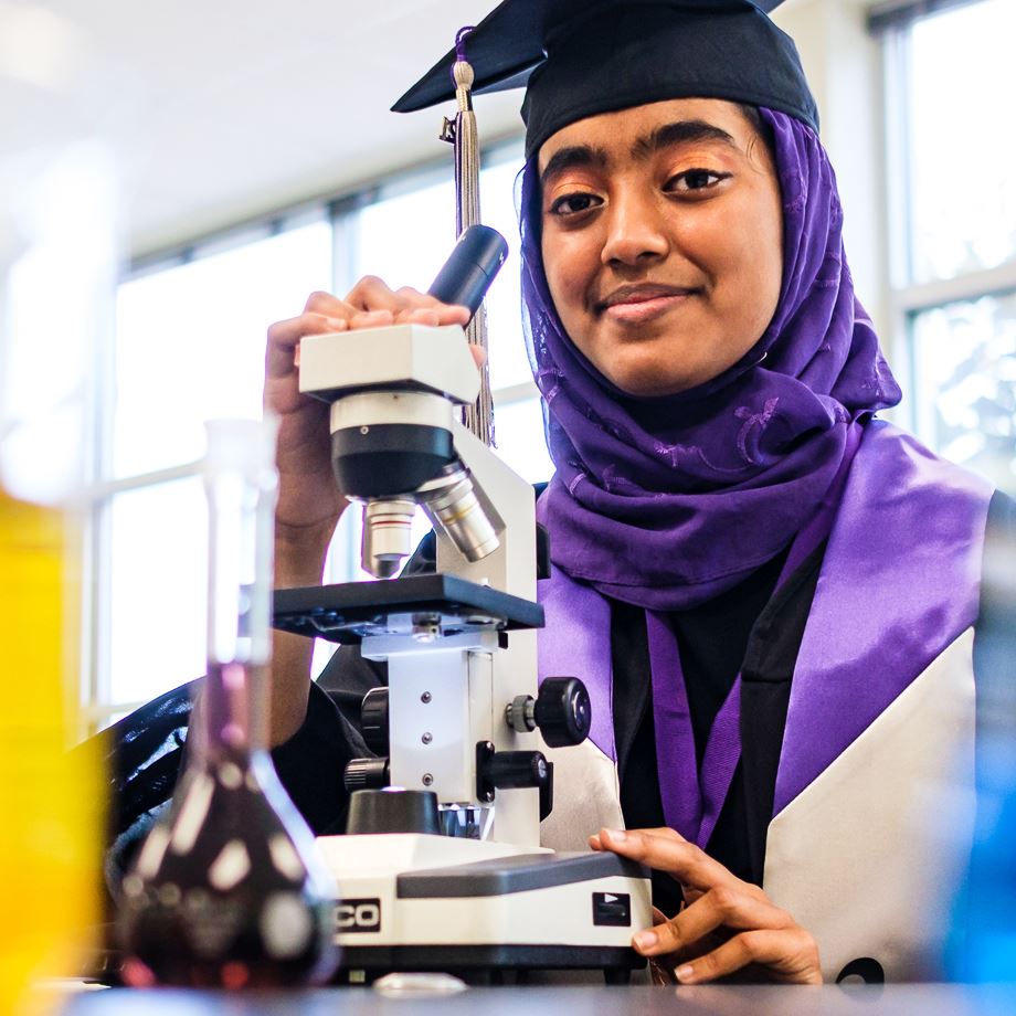 South Garner High graduate Fariha Begum with a microscope and scientific beakers